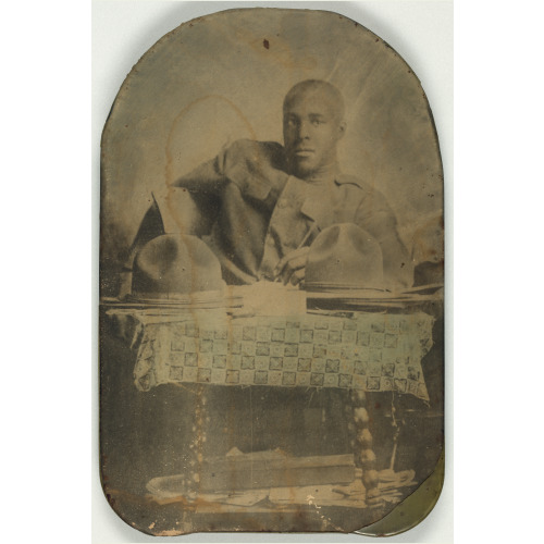 World War I Soldier, Half-Length Portrait, Seated, Facing Front, With Two Hats On Table, circa 1917