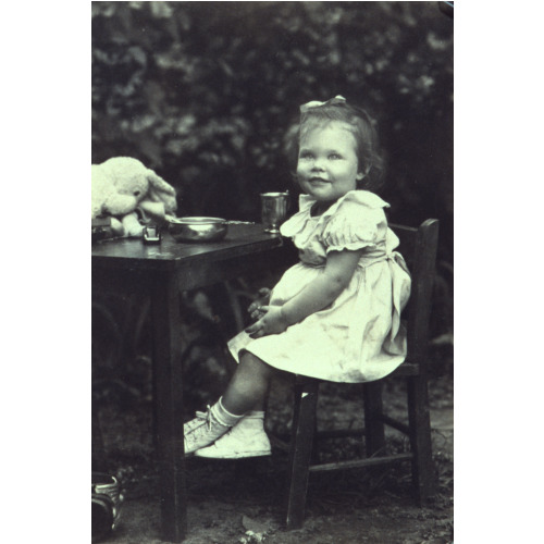 Portrait Of A Young Girl Seated At An Outdoor Table, Facing Front, circa 1940