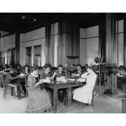 Interior View Of Library Reading Room With Male And Female Students Sitting At Tables, Reading...